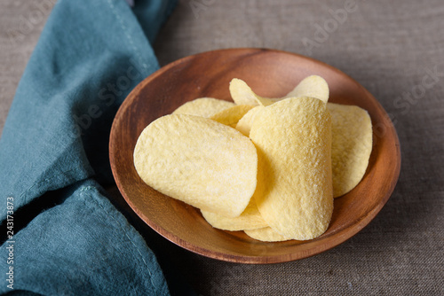 Crispy potato chips in wooden bowl with napkin