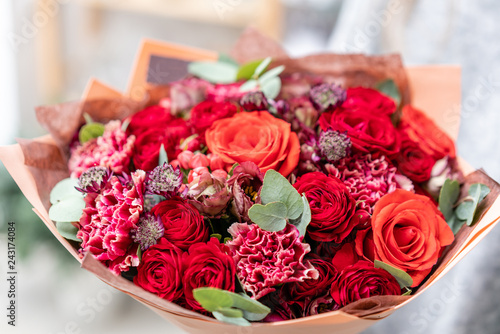 beautiful fresh cut bouquet of mixed flowers in woman hand. the work of the florist at a flower shop. Bright juicy red colors