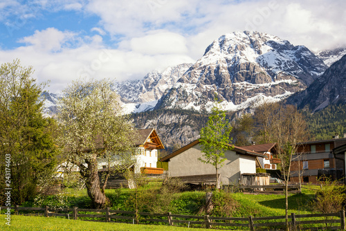 View of the village of Ehrwald (Austria) and its beautiful surrounding mountains (Zugspitze Arena) and green alp meadows. Shot in afternoon sunlight.