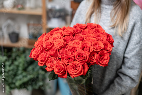 Red roses in glass vases in womens hands. Bunch scarlet red. the concept of a florist in a flower shop. Wallpaper.