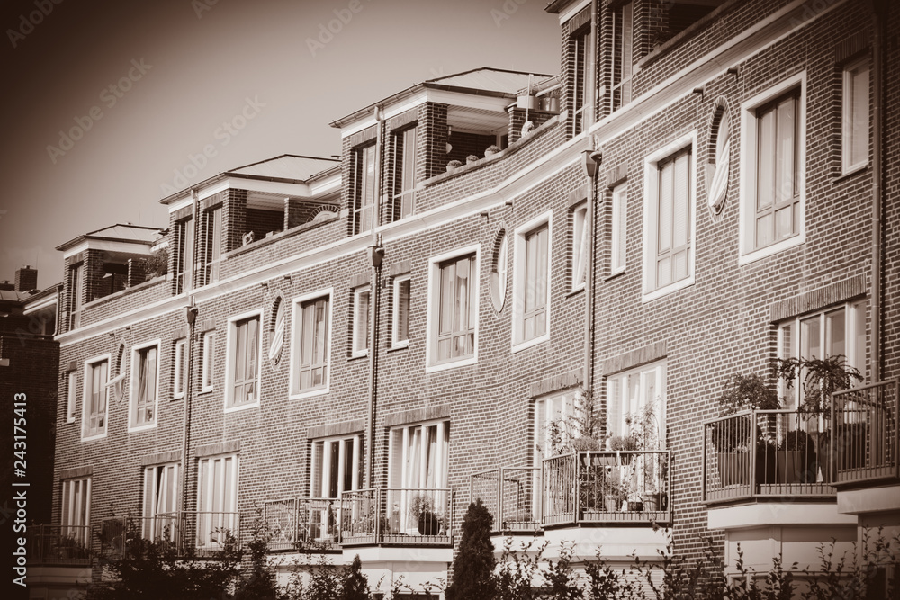 View at red brick house with balcony and plants in sunny day in Bremen, Germany . Image in sepia color style