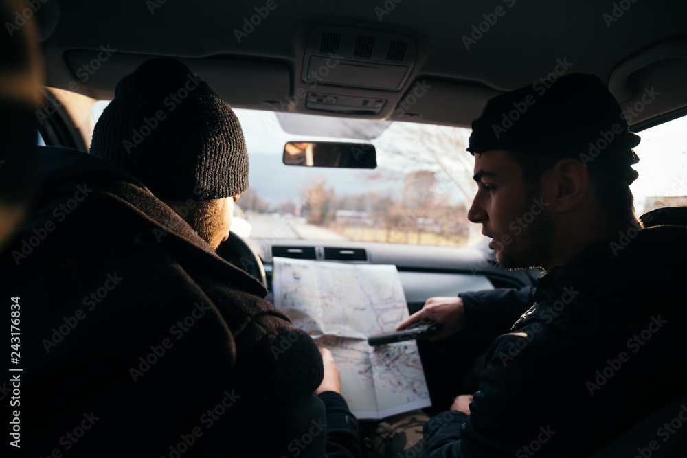 Two Robbers looking at a map and planning their next robbers,one of them is holding a gun.