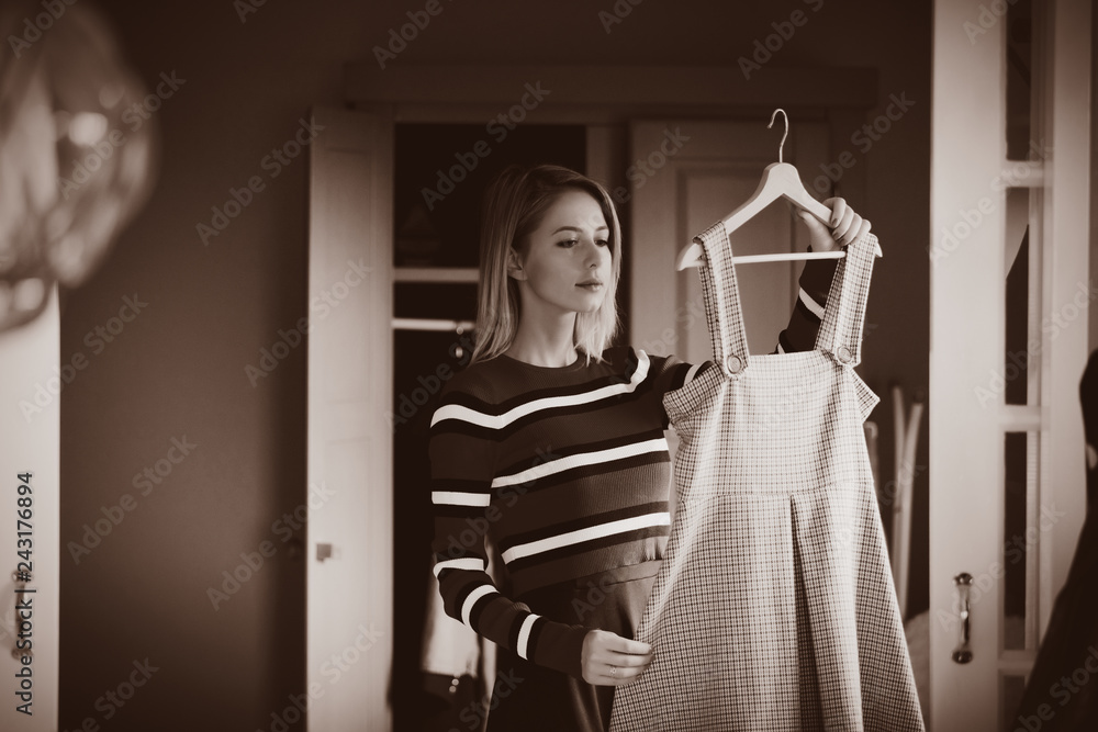 Young girl choose a dress at home near wardrobe in bedrood. interior in Dutch style . Image in sepia color style Young girl choose a dress at home near wardrobe in bedrood. interior in Dutch style . Image in sepia color style
