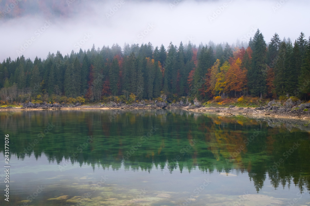 Reflections of foggy forest on lake Laghi Fusine in autumn
