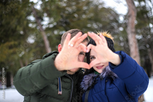 Young couple make heart shape by fingers.