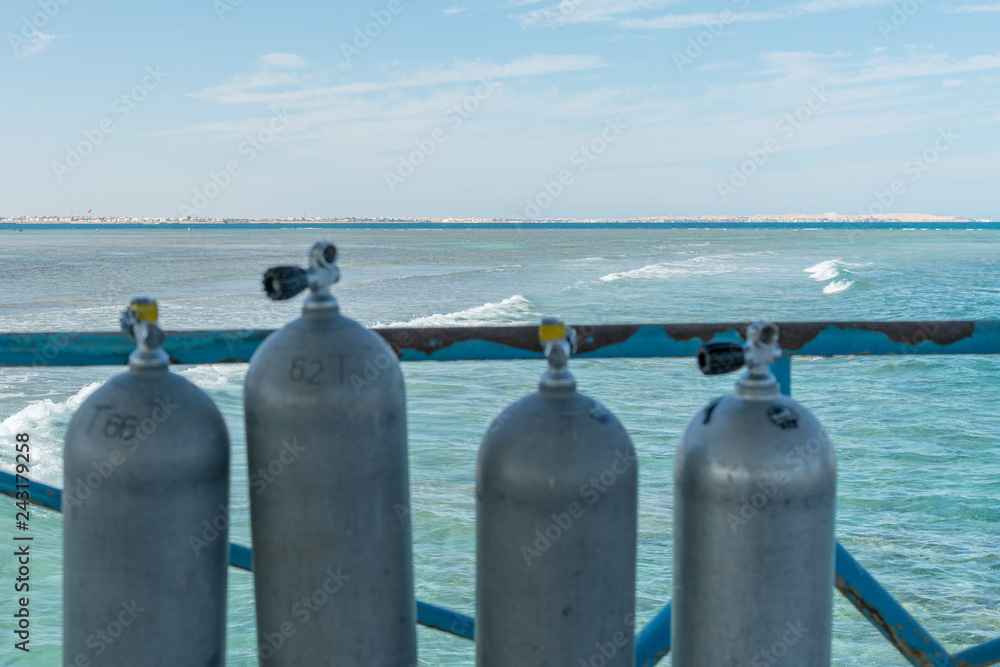 A lot of diving cylinders. oxygen cylinders outdoor. Oxygen cylinders for swimming in the background of the sea. A lot of diving cylinders. oxygen cylinders outdoor. Oxygen cylinders for swimming in the background of the sea.