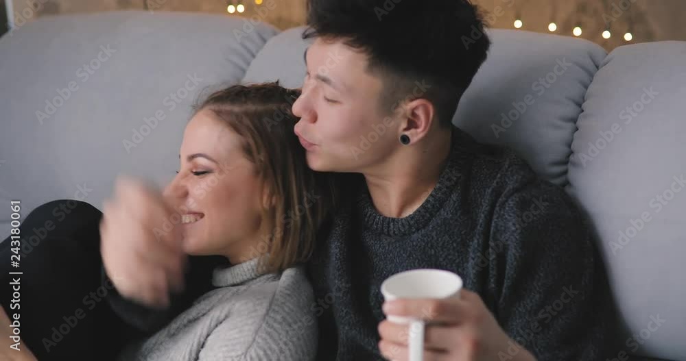 Love, relationship, young happy couple show their feelings together at home sitting on a cozy sofa in a living room Love, relationship, young happy couple show their feelings together at home sitting on a cozy sofa in a living room
