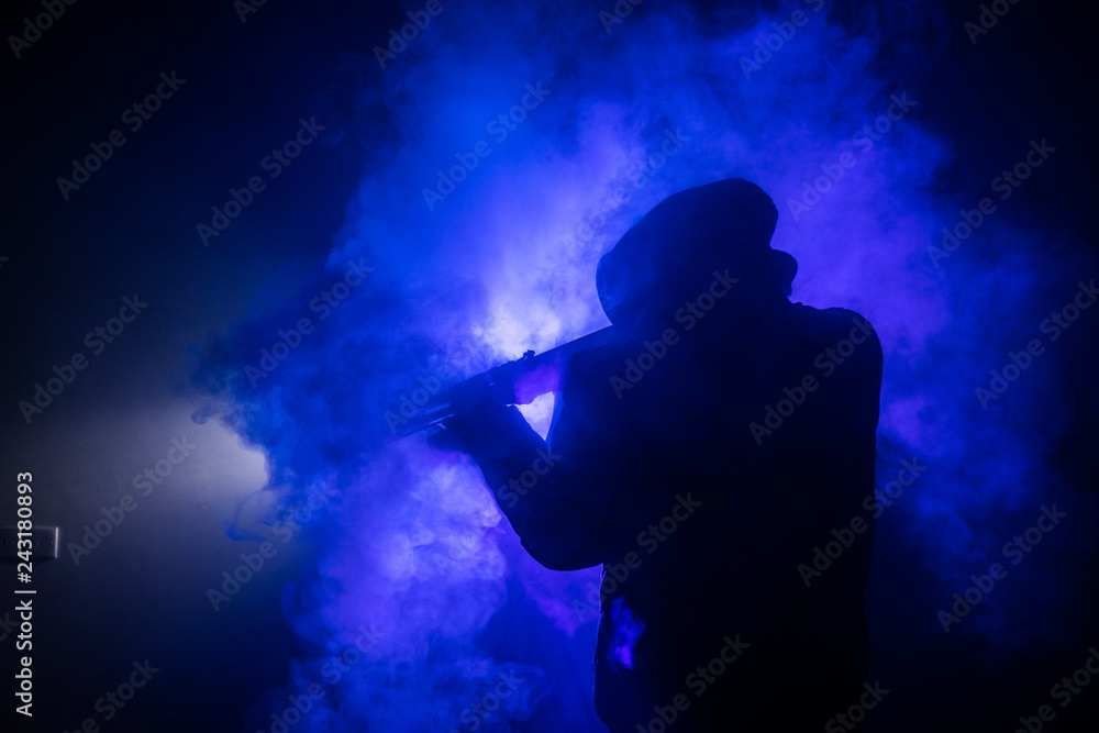 Silhouette of man with assault rifle ready to attack on dark toned foggy background or dangerous bandit in black wearing balaclava and holding gun in hand. Shooting terrorist with weapon theme decor Silhouette of man with assault rifle ready to attack on dark toned foggy background or dangerous bandit in black wearing balaclava and holding gun in hand. Shooting terrorist with weapon theme decor