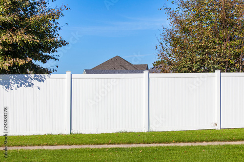 Bild auf Leinwand White vinyl fence spanning across the back yard of a home