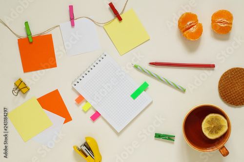 Flat lay of multicolored paper stickers with clothespins, tea and stationery