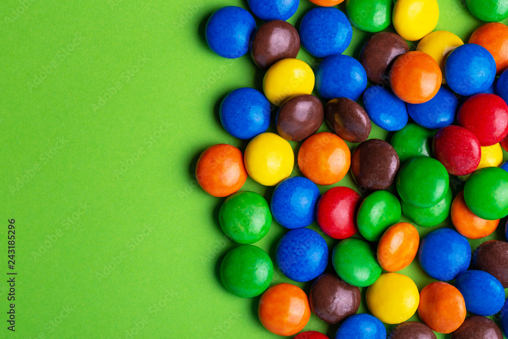 Glazed colored chocolate candies are gathered on bright green background Glazed colored chocolate candies are gathered on bright green background