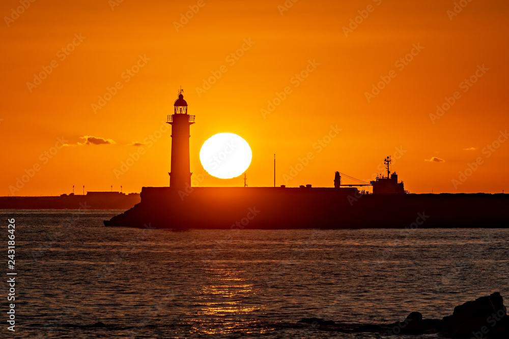 Orange sunset next to lighthouse.