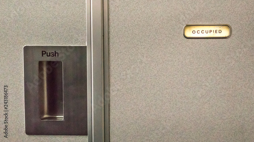 Close up of an airplane lavatory door, with occupied sign on.