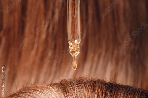 Fotografie Close-up drop of oil restore and recovery hair is applied to head bulbs