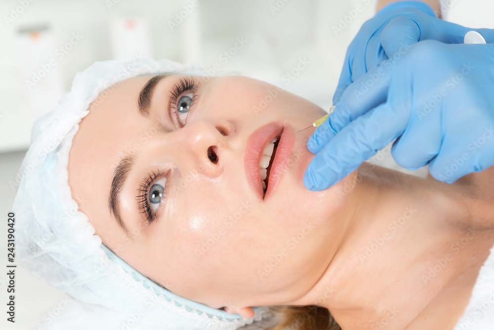 The doctor cosmetologist makes the Rejuvenating facial injections procedure for augmentationon  lips of a women in a beauty salon.Cosmetology skin care.