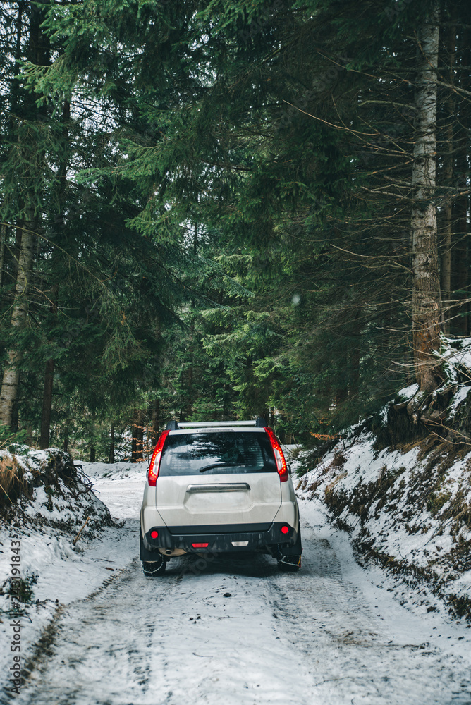 Fototapeta premium suv car with chain on wheels in snowed forest