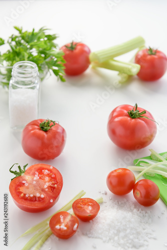 The most useful juice. Tomato juice from fresh tomatoes. Tomato juice in glass with celery, cherry tomato, white wood background, closeup