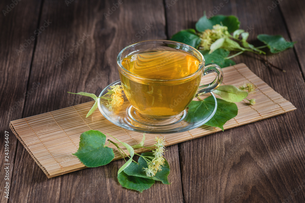 Tea with linden and lemon. Cup with fragrant lime tea, standing on a wooden table, in the rays of sunlight. Tea with linden and lemon. Cup with fragrant lime tea, standing on a wooden table, in the rays of sunlight.