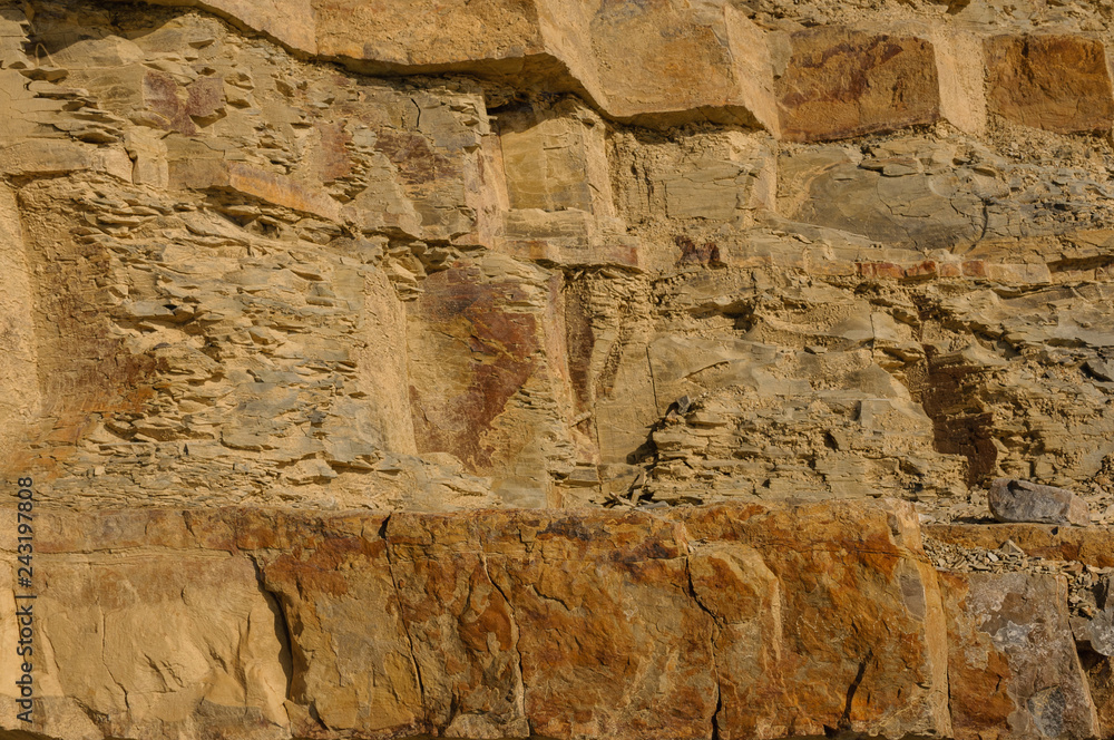 Texture of a yellow rock rock or background for design..Surface of the wall with textured surfaces for tiles.