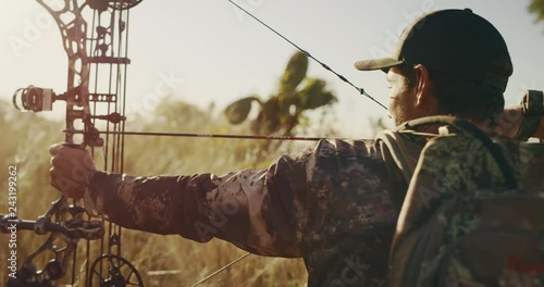 Orbit shot of bowhunter with arrow drawn then unloading his bow photo