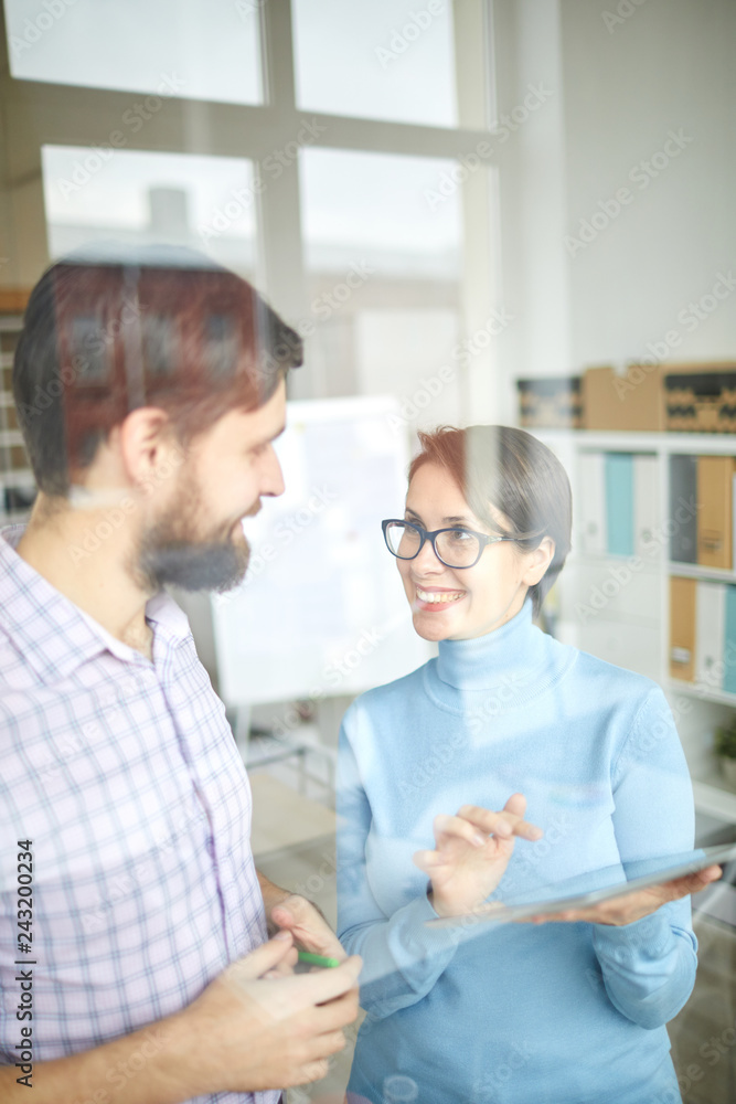 Cheerful businesswoman with tablet showing her colleague and explaining online financial data at working meeting Cheerful businesswoman with tablet showing her colleague and explaining online financial data at working meeting