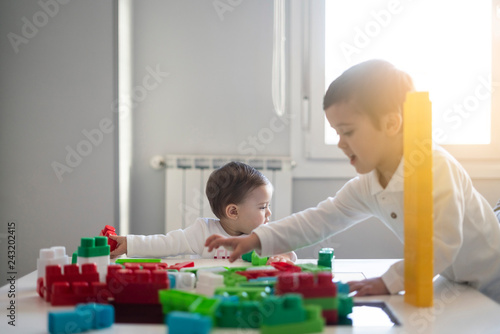 Two happy baby playing with toy blocks.