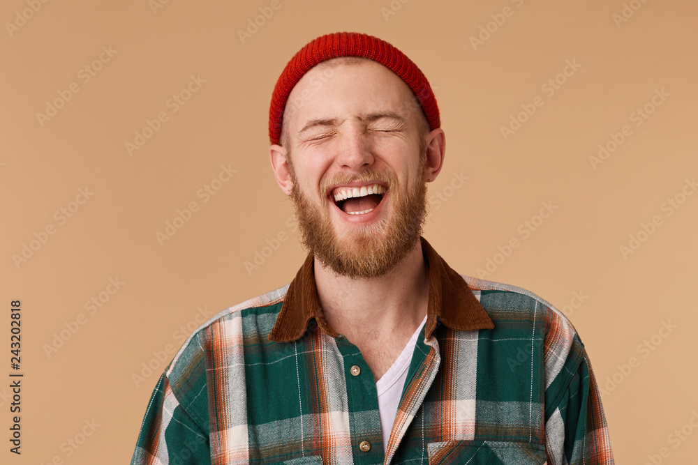Attractive young man laughing with closed of joy eyes. Handsome male person showing his teeth while laughing on new joke.Happiness and positive emotions concept Attractive young man laughing with closed of joy eyes. Handsome male person showing his teeth while laughing on new joke.Happiness and positive emotions concept