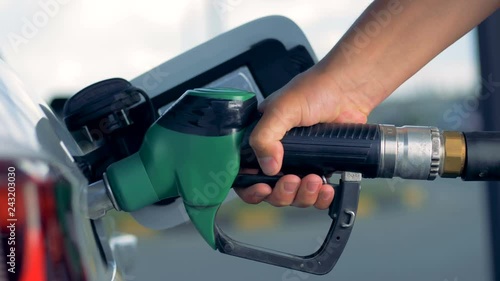 An automobile is getting refueled by a petrol pistol  photo