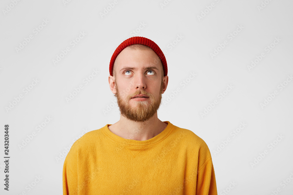 Close up of a guy with a slight smile, surprise, looks up at the empty space for copy. Bearded man with a fascinated look raised his head up saw something unusual isolated on white background Close up of a guy with a slight smile, surprise, looks up at the empty space for copy. Bearded man with a fascinated look raised his head up saw something unusual isolated on white background