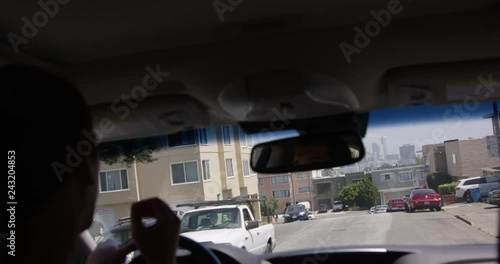 Man driving car through on suburban street - view from the back seat looking out windsheild photo