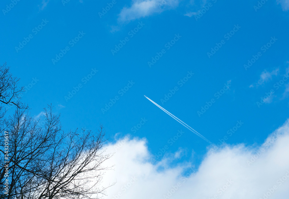 Airplane flying in the blue sky among clouds and sunlight Airplane flying in the blue sky among clouds and sunlight