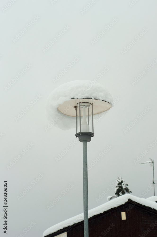 Beautiful white snow on the gray lantern of the streetlight outdoor. Snowy weather condition. Winter concept. Beautiful white snow on the gray lantern of the streetlight outdoor. Snowy weather condition. Winter concept.