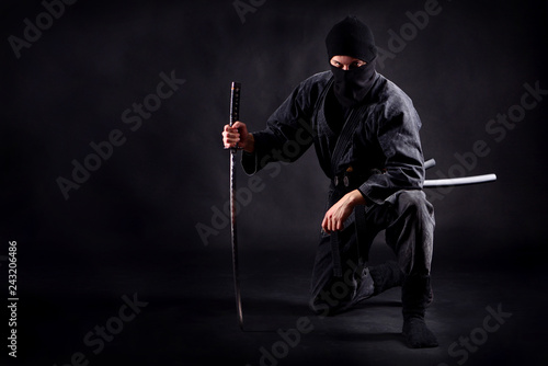 Ninja samurai crouched on one leg and propped on a sword