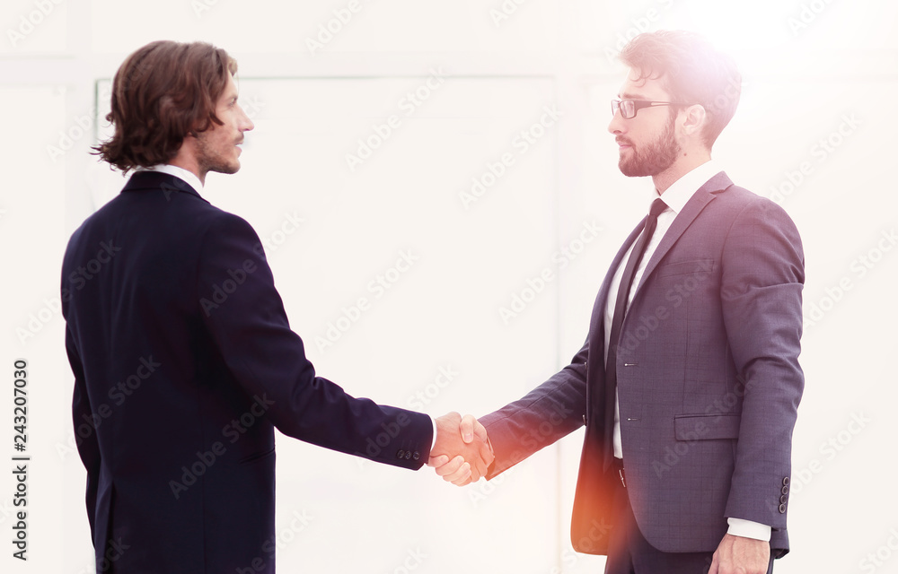 Two young businessmen greet