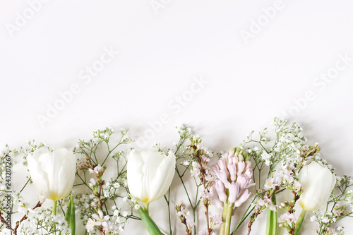 Fototapeta Naklejka Na Ścianę i Meble -  Easter floral frame, web banner. Spring wedding, birthday composition with pink hyacinth, cherry blossoms, white tulips and baby's breath flowers. White table background. Flat lay, top view.