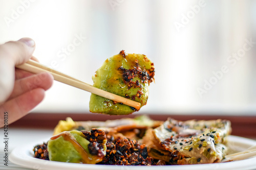 Chopsticks holding a vegetarian dumpling photo