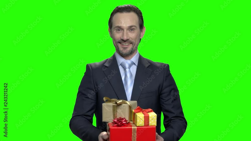 Cheerful man in business suit with gift boxes. Green hromakey background for keying. Cheerful man in business suit with gift boxes. Green hromakey background for keying.