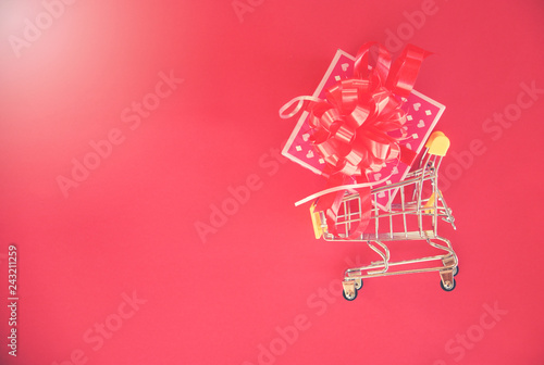 Valentines day shopping and Gift Box / Pink present box with red ribbon bow on shopping cart