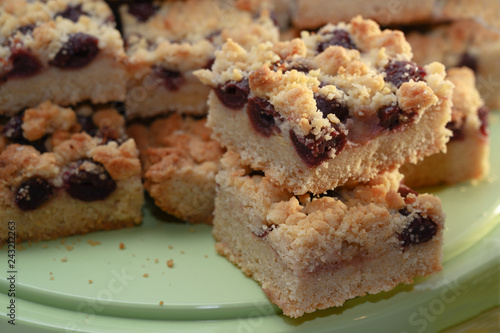 homemade crumble cake with cherries on a green plate