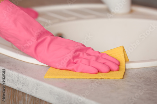 Woman cleaning sink with rag in kitchen, closeup