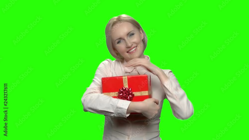 Lovely mature business woman adore her red gift box. Green hromakey background for keying. Lovely mature business woman adore her red gift box. Green hromakey background for keying.
