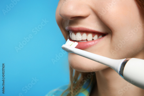 Young woman with electric toothbrush on color background, closeup. Space for text