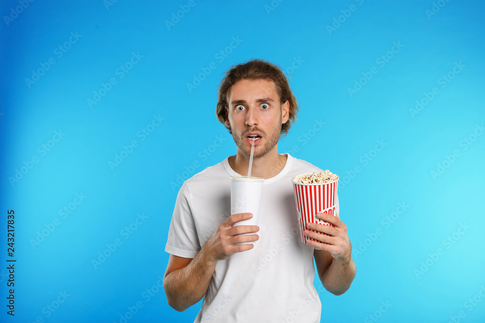 Naklejka premium Emotional man with popcorn and beverage during cinema show on color background