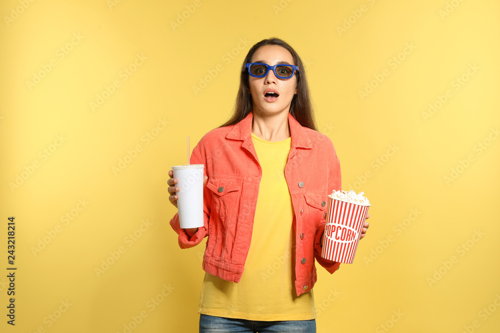 Fototapeta premium Emotional woman with 3D glasses, popcorn and beverage during cinema show on color background
