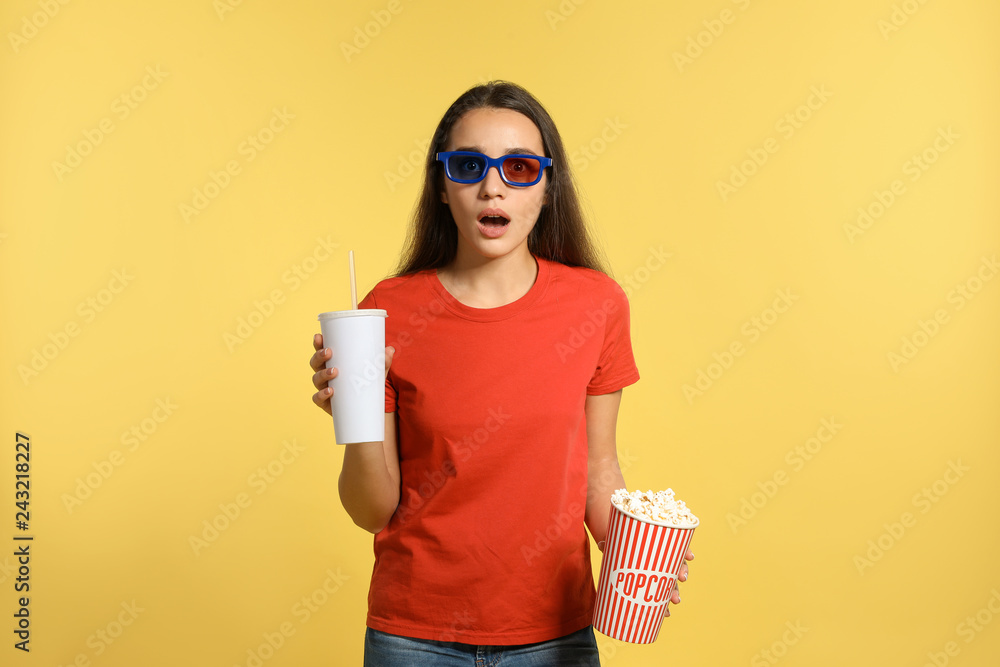 Fototapeta premium Emotional woman with 3D glasses, popcorn and beverage during cinema show on color background