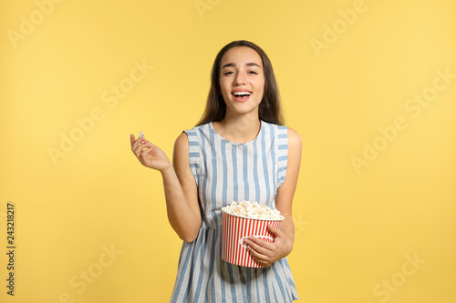 Woman with popcorn during cinema show on color background