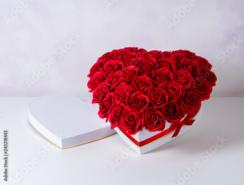 Flowers as a gift: A large bouquet of red roses in a white box with a red ribbon on a white background. #243218443