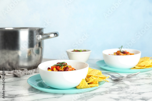 Bowl with tasty chili con carne served on marble table