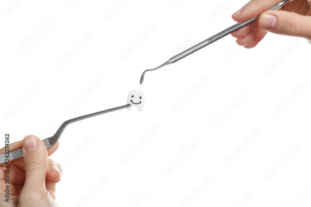 Woman holding professional dental tools and small plastic tooth on white background Woman holding professional dental tools and small plastic tooth on white background