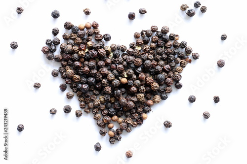 Heart made of black peppercorns on white background